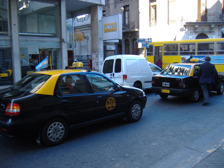 Vehículos circulando y estacionados en una calle de Rosario.