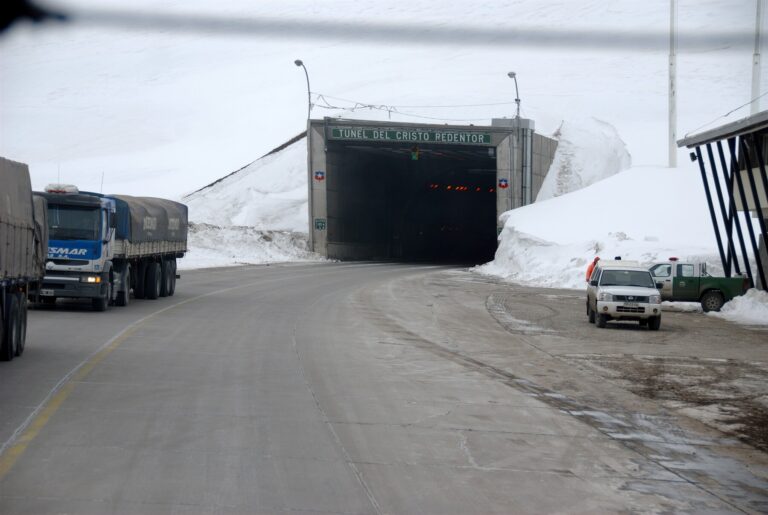 Acceso nevado al Túnel Internacional Cristo Redentor con camiones en la calzada.