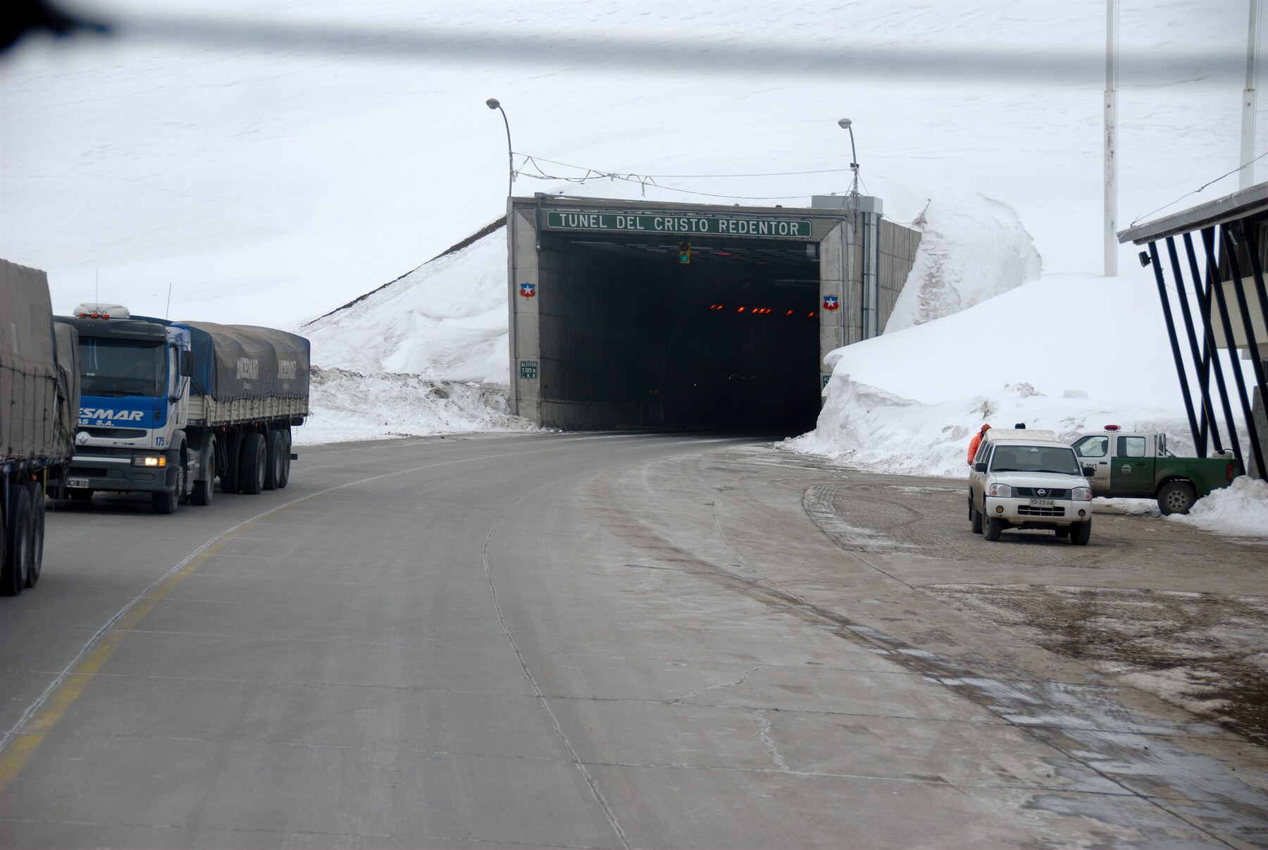 Acceso nevado al Túnel Internacional Cristo Redentor con camiones en la calzada.
