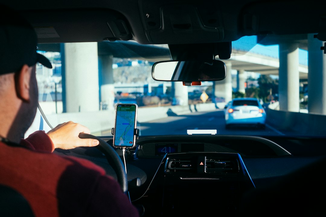 Conductor utilizando un teléfono móvil dentro de un automóvil, imagen ilustrativa sobre plataformas de viajes